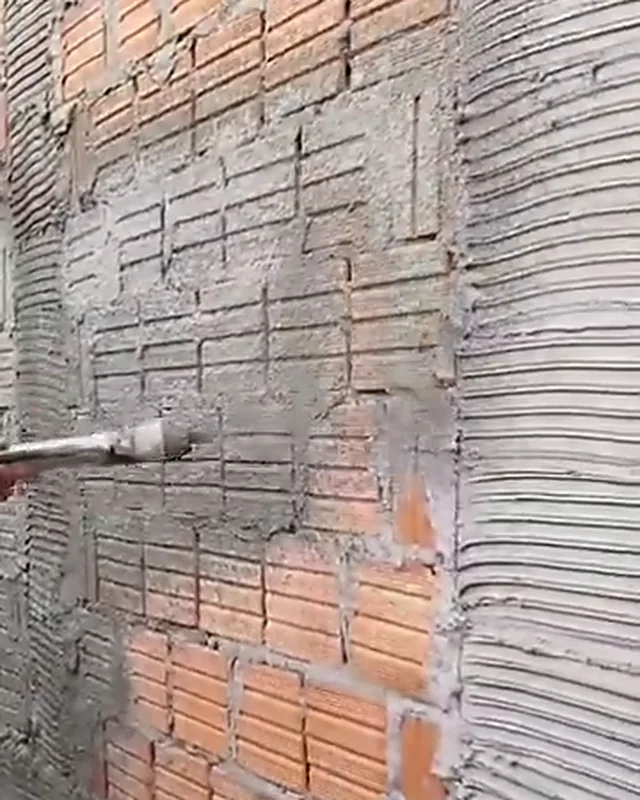 Reboco sendo projetado sobre parede de tijolo